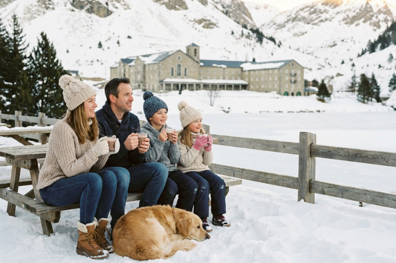 عائلة عربية تستمتع بشرب الشوكولاتة الساخنة أمام مبنى مزار وادي نوريا والبحيرة المتجمدة في الشتاء.
