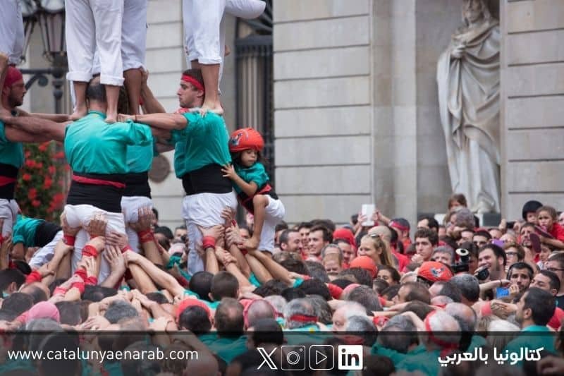 مشاركون في تقليد الأبراج البشرية Castells في كتالونيا يبنون برجاً بشرياً متعدد الطبقات وسط حشد من الجمهور